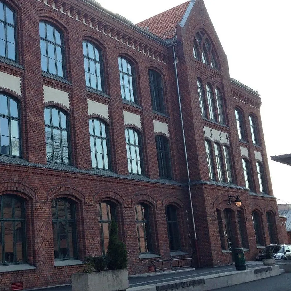 Restaurert teglbygning med høye buede vinduer og klassiske murdetaljer i historisk arkitektur.