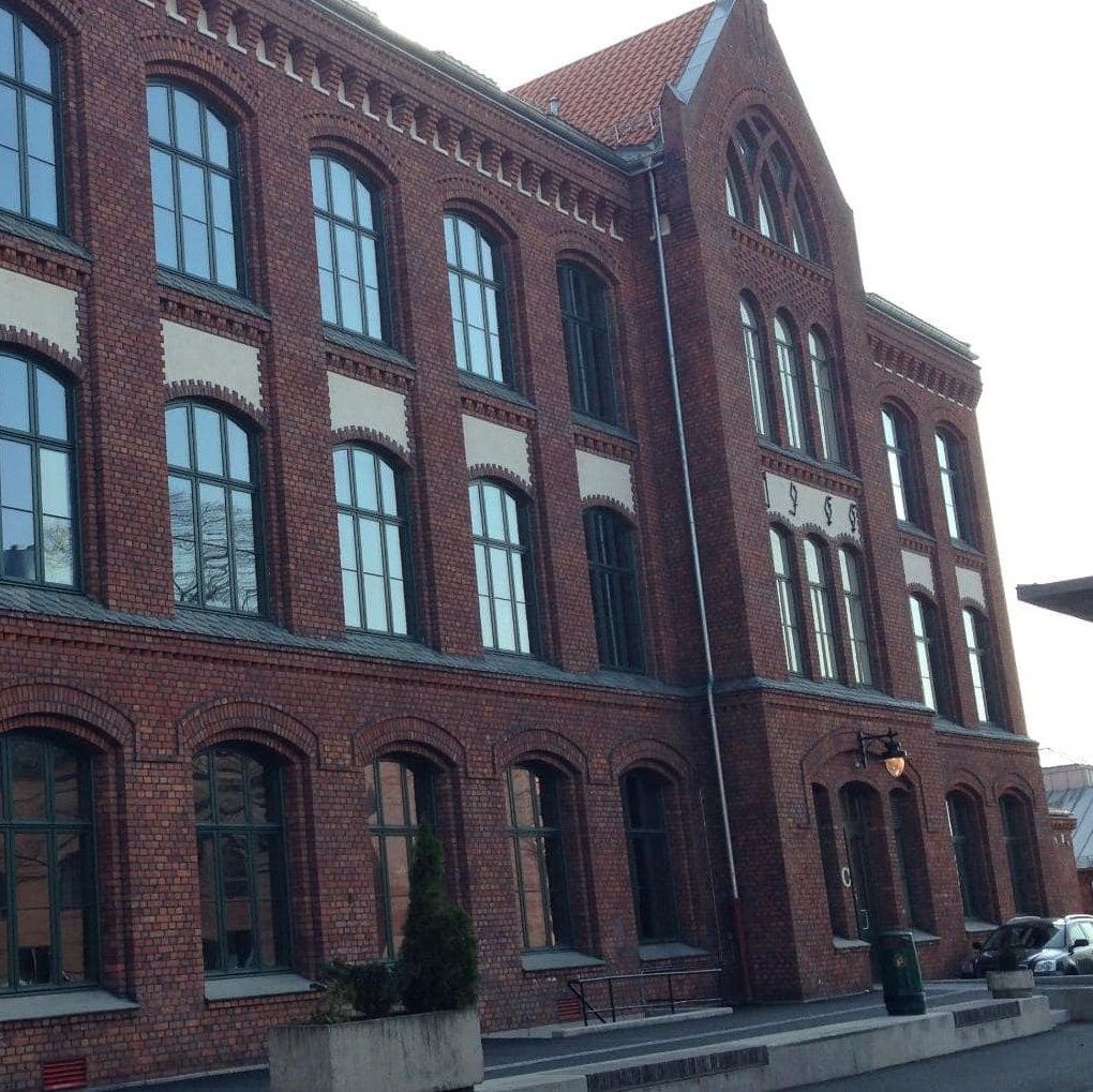 Restaurert teglbygning med høye buede vinduer og klassiske murdetaljer i historisk arkitektur.